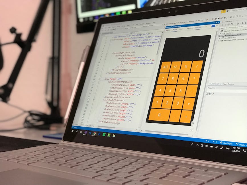 A laptop displaying code editor and a calculator app open on the screen, set in a workspace environment. The code editor shows lines of HTML or CSS, with colorful syntax highlighting indicating a focu